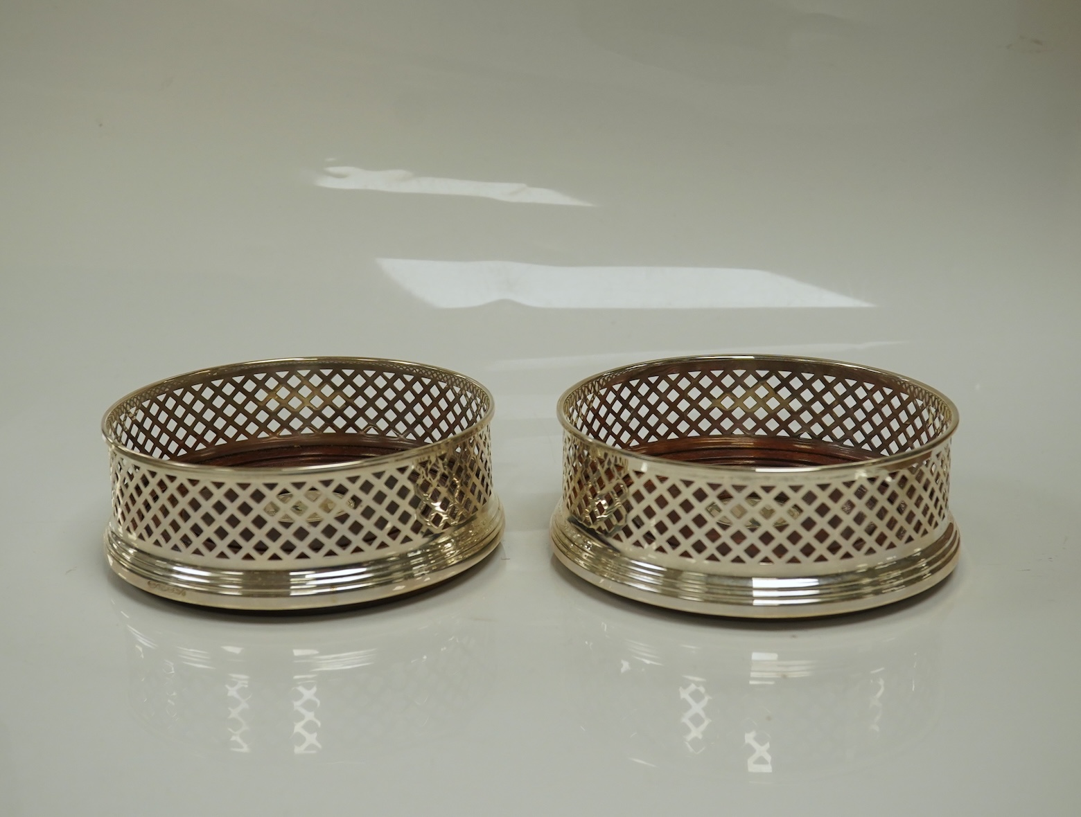 A pair of modern pierced silver mounted wine coasters, by W.I. Broadway & Co, Birmingham, 2000, diameter 12.2cm. Condition - good